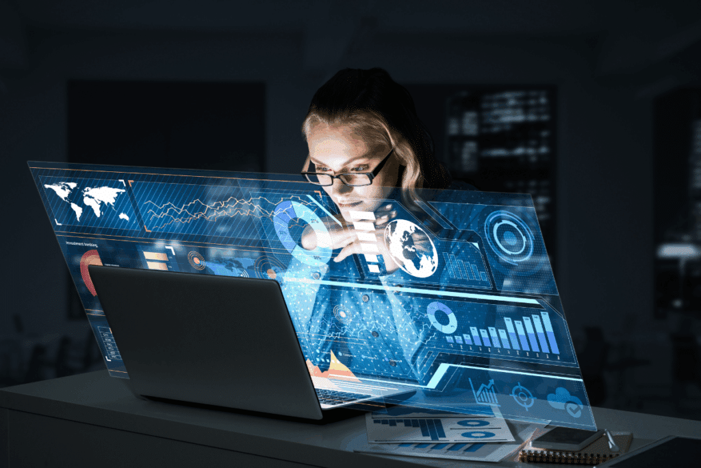 Mulher loira de óculos analisando gráficos, mapas globais e dados financeiros em uma tela holográfica futurista no notebook.