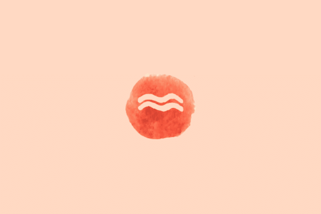 Ilustração do signo de Aquário sobre fundo uniforme em tom pêssego-claro. No centro, há um círculo irregular em vermelho vivo, com textura de aquarela e bordas levemente desiguais. O símbolo de Aquário aparece em tom creme, formado por duas linhas onduladas horizontais, posicionadas uma acima da outra. As curvas são suaves e paralelas, representando o símbolo tradicional do signo.