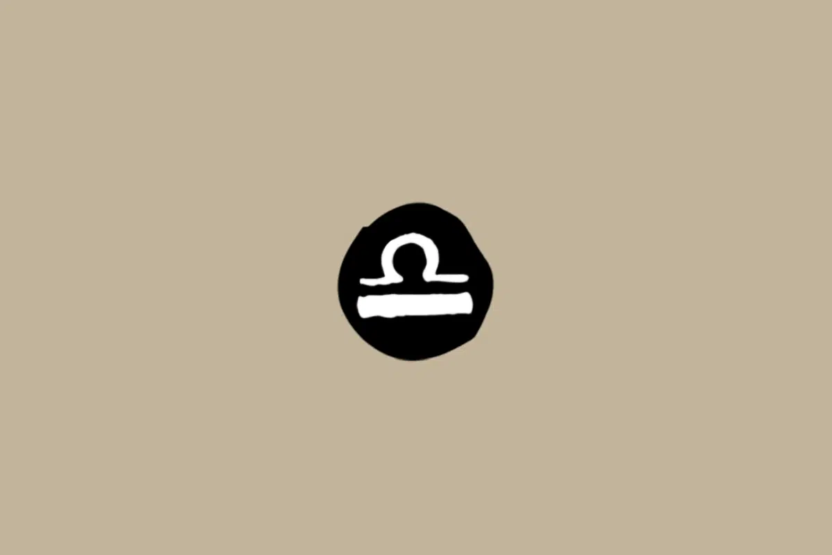 Símbolo do signo de Libra em branco dentro de um círculo preto sobre um fundo bege 