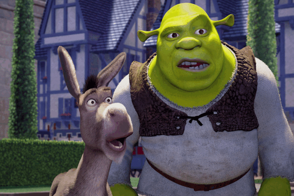 Cena do filme Shrek: o ogro verde Shrek e o Burro, lado a lado, olham espantados para algo fora da imagem, em frente a casas e muros de um reino.